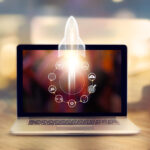 Startup concept. Laptop on wooden table and and icon network connection with rocket icon flying out of screen